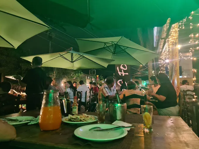 Área externa da O Forno Pizzaria com mesas e iluminação noturna